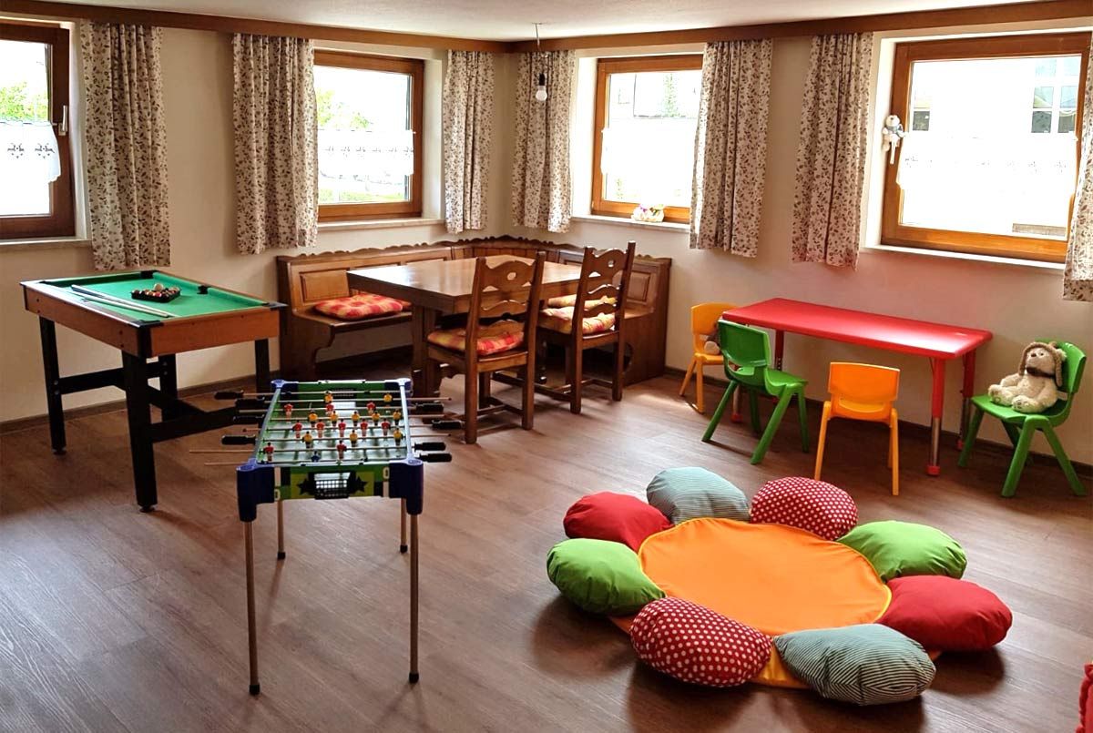 Spielzimmer mit Tisch, Stühle, Eckbank sowie Tischkicker und Billiard