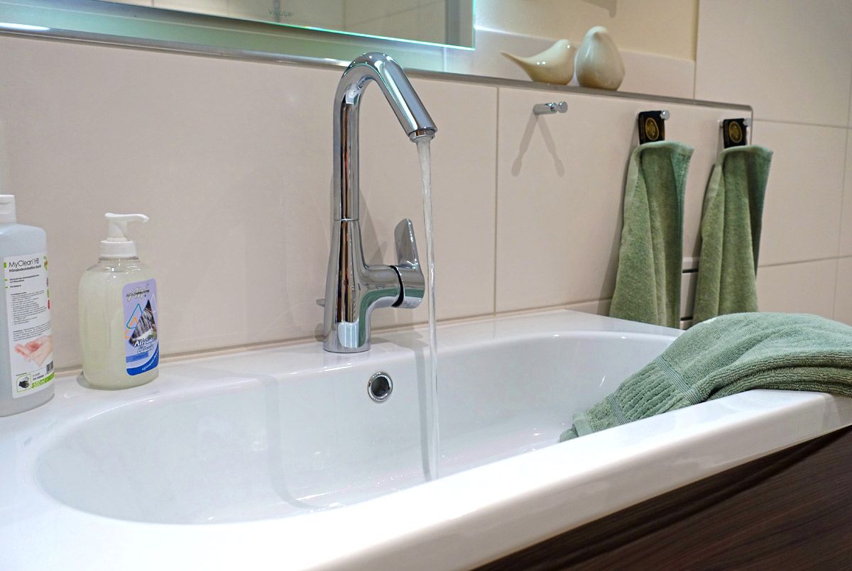 Waschbecken mit beleuchtetem Spiegel mit Seife und Handtüchern