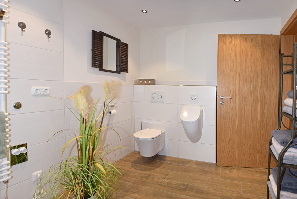 Großes Badezimmer mit WC, Pissior, Heizkörper und Spiegel